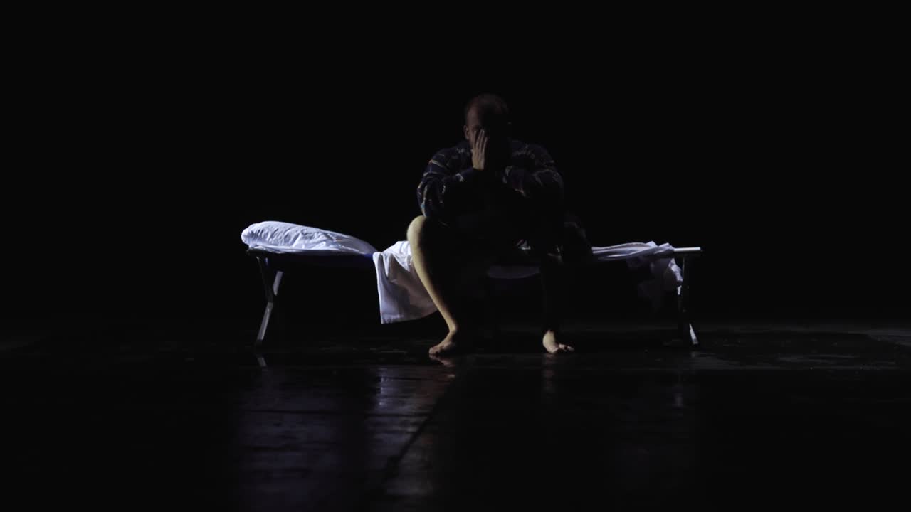 Man Sitting Alone on a Camping Bed