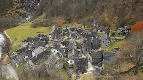 un avión no tripulado gira sobre el río maggia que fluye a lo largo de las casas de la aldea en cavergno, distrito de vallemaggia en el cantón de ticino, suiza durante el día