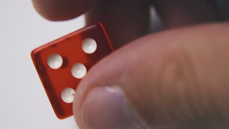 man turns dice with five spots on side against white surface