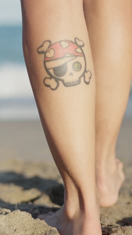 pirate skull tattoo on leg at beach