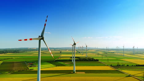 enormous agricultural fields with wind farms. multiple wind turbines producing clean energy.