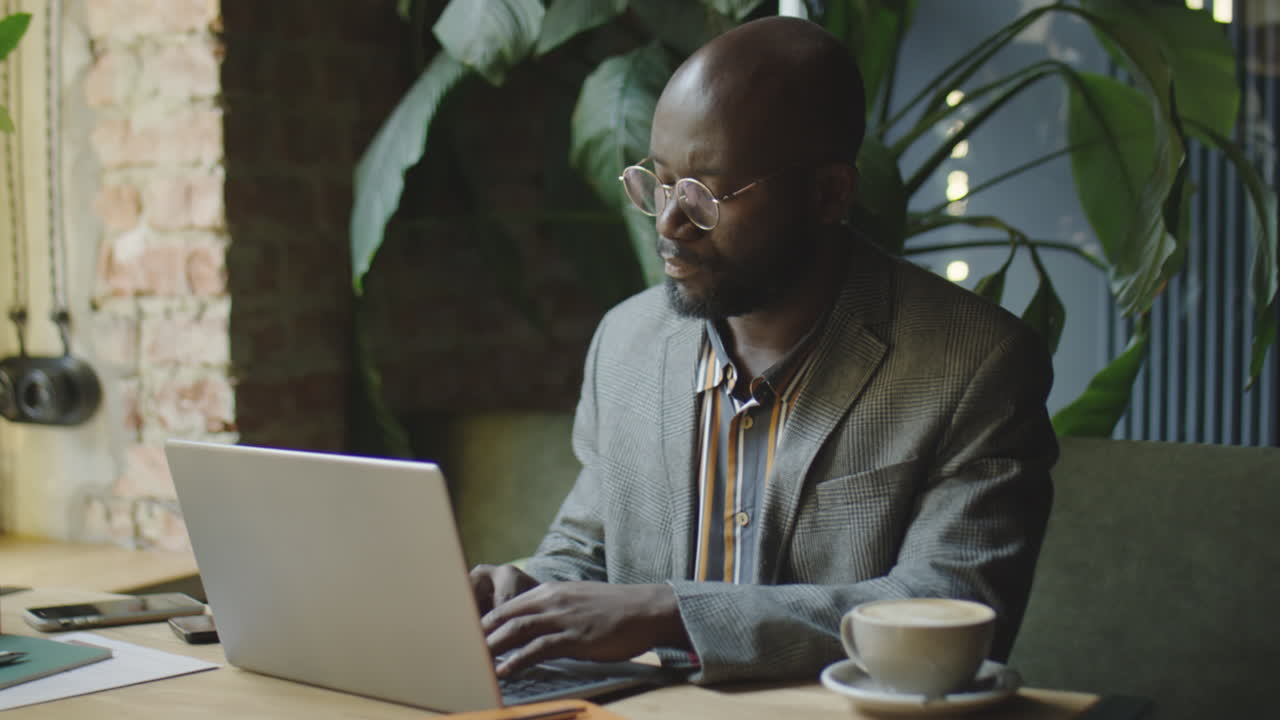Black Businessman Working on Laptop at Coffeeshop Table