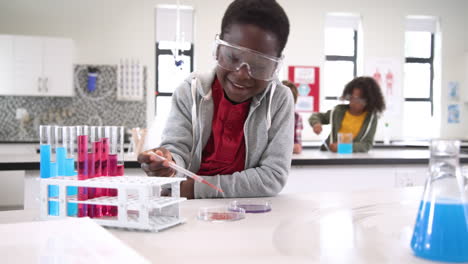 student in science class experimenting with test tubes, wearing safety goggles