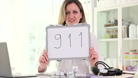 woman holding a whiteboard with '911' written on it in a medical setting