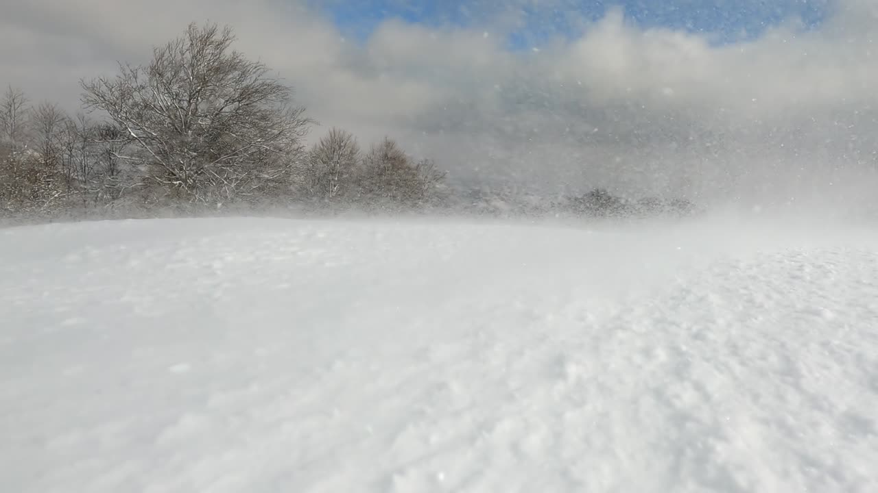 Snow surface of snowdrifts on winter mountain ski slope, closeup. Slow motion