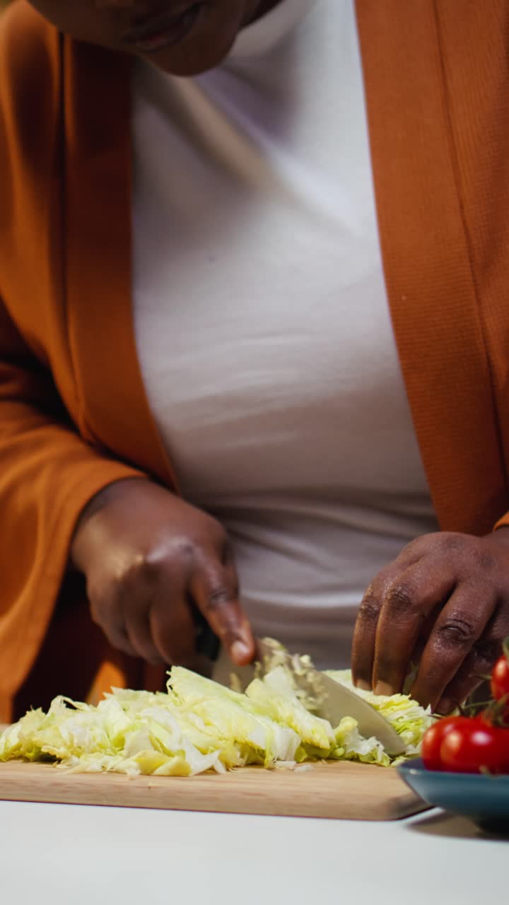 Video verticale. Food blogger di colore taglia lattuga iceberg sul tagliere