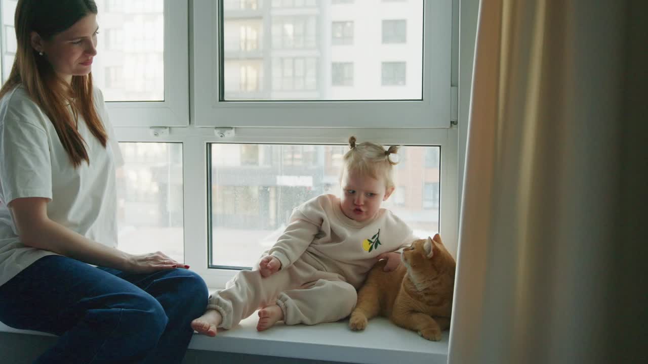 Young Woman and Toddler with Cat Sitting on Windowsill