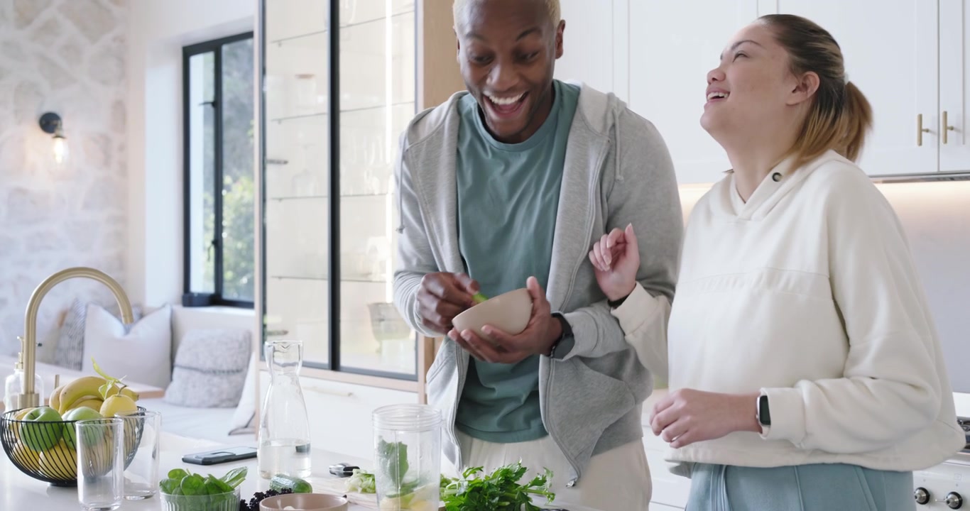 African American couple mixing greens, man placing blender cup then handing herbs and pouring water
