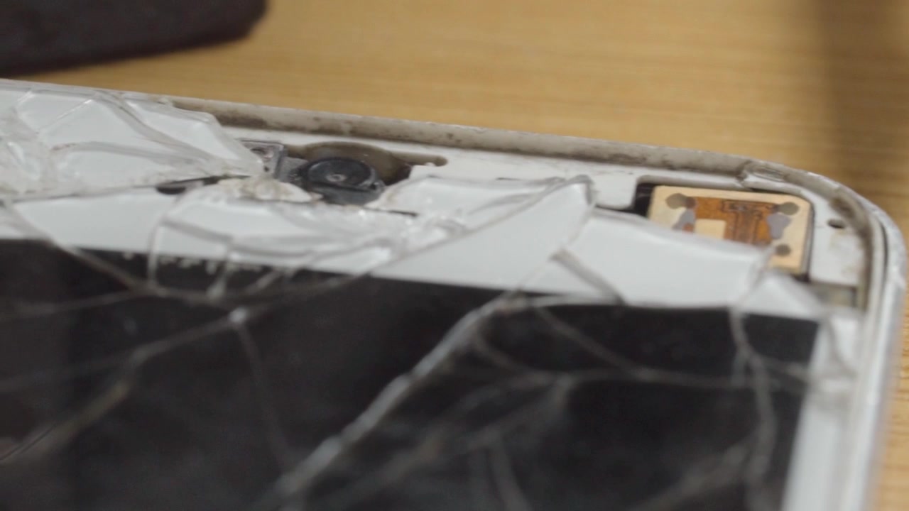 Closeup of cracked smartphone screen showing broken glass and damaged display after accidental drop. Mobile device requiring repair or replacement due to impact damage