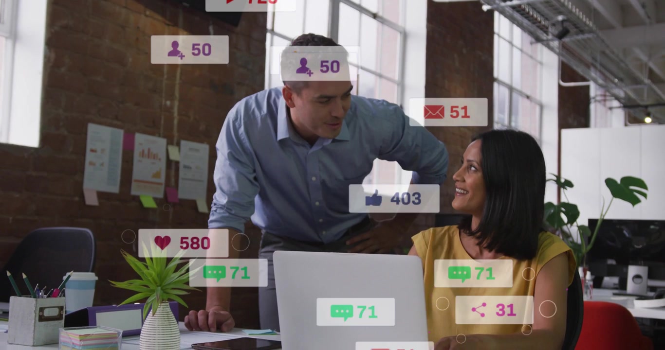 Vertical video: Leaning blue shirt man and woman at desk, alerts rising on laptop tracking reach