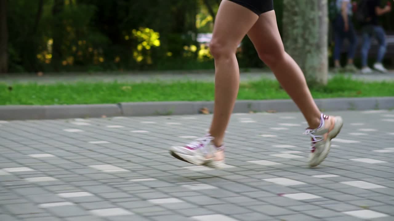 Close Up of female athlete's feet running at the park. Fitness woman jogging outdoors. Exercising on park pavement. Healthy