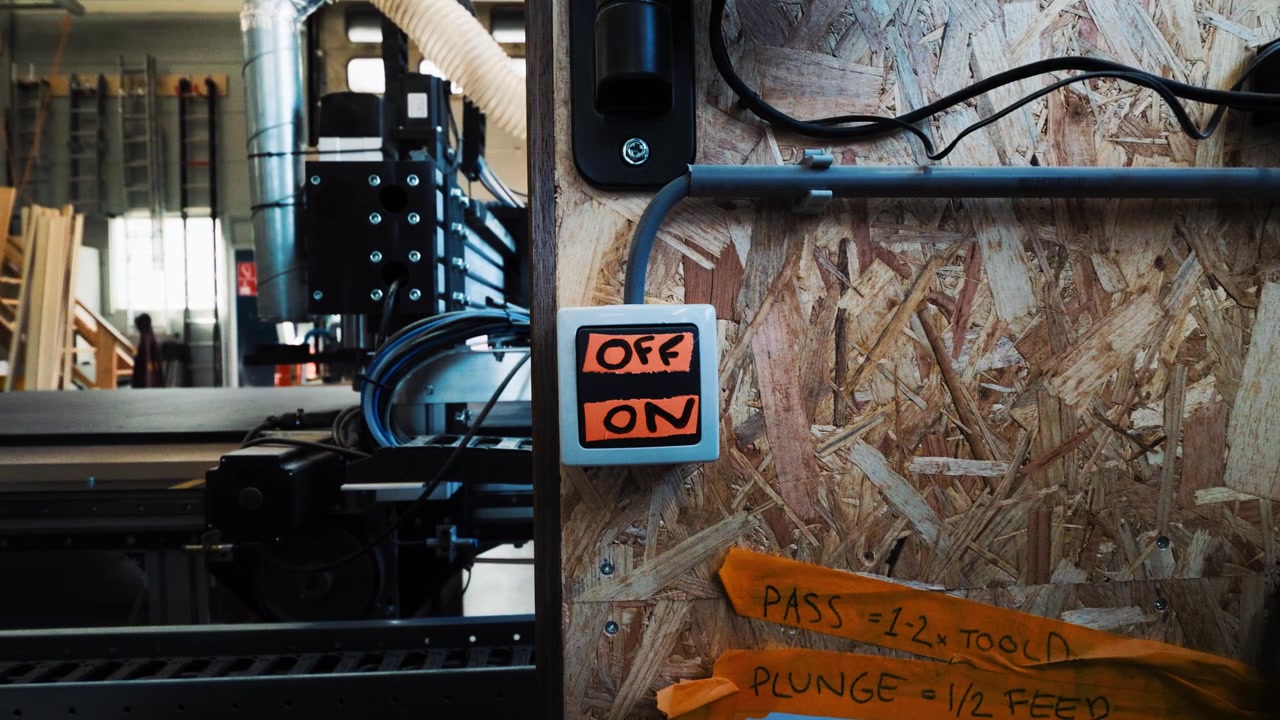 Dettaglio di una parete di officina con comandi macchina e un timer accanto a una parte di un grande sistema CNC.