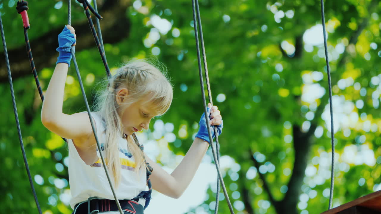 un niño valiente camina por la cuerda floja entre árboles altos infancia activa y diversión
