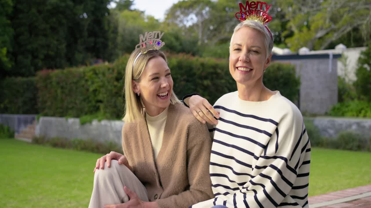 Veninder smiler og deler juleglæde med pandebånd på en havebænk