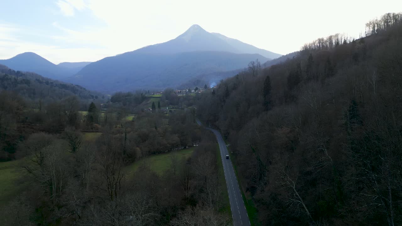 Aerial view of a mountain valley with a winding road and village