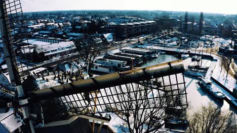 Great-Cormorant-Bird-Colony-Perched-on-Snow-Covered-Windmill-in-Harderwijk,-Drone-View