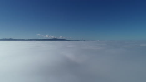 drone accent through white clouds revealing beautiful blue sky and rolling hills in the distance