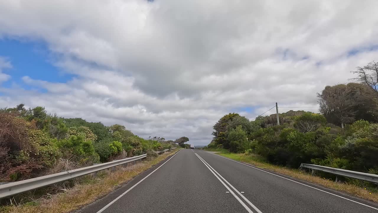 A serene drive through lush greenery and open roads under a partly cloudy sky on the Great Ocean Road