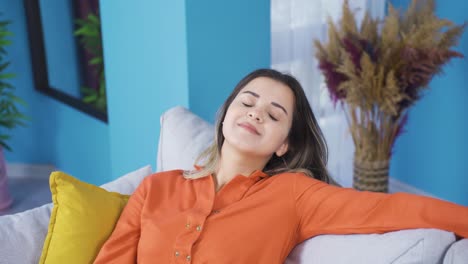una joven relajada y pacífica está descansando en el sofá.
