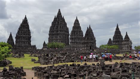 indonesia,prambanan temple on a cloudy day from a distance, camera tits up slowly, people walking around the temple complex in slow motion. covering all temple complex.