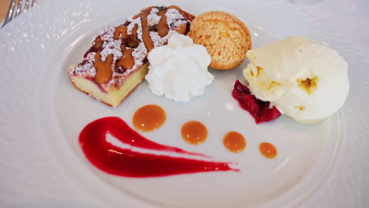 Close up of a dessert plate with a tart, a cream puff, ice cream, and sauces