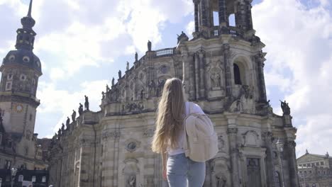 a young woman is admiring the stunning historic buildings while exploring a vibrant city square beneath a blue sky