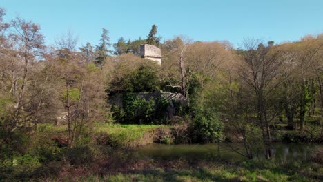 Slow-aerial-dolly-towards-a-broken-tower-and-remains-of-a-building-beside-a-river