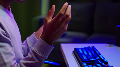 un joven jugando a videojuegos en su computadora en casa.