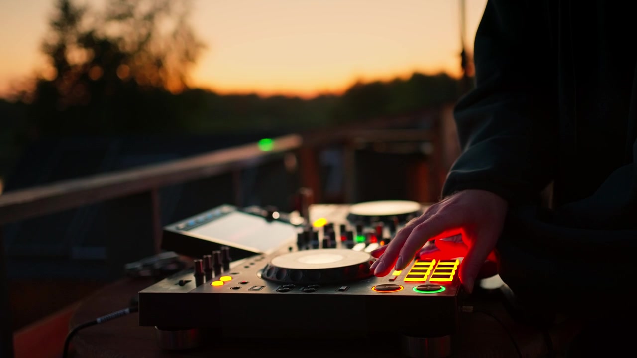 DJ mixer musik på controller ved solnedgang
