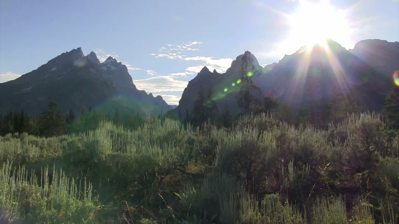 그랜드 테톤 산맥 위로 엿보는 태양을 가로질러 팬