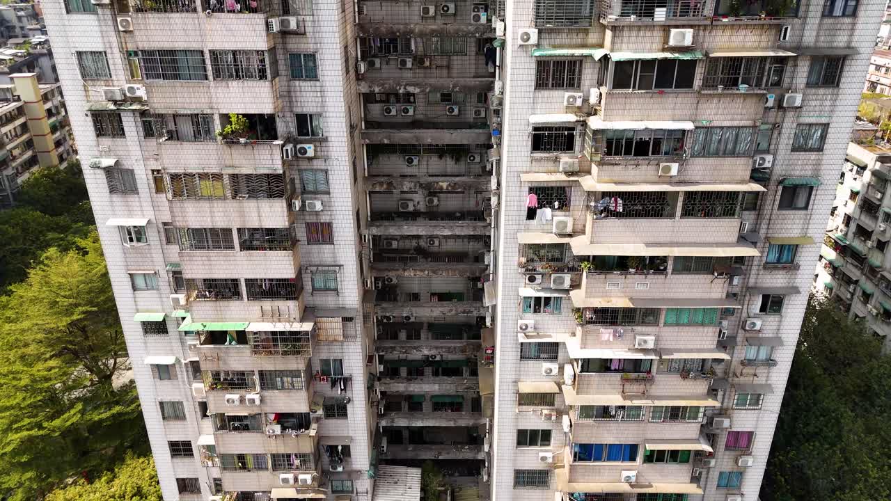 An old apartment building in Guangzhou, China, with numerous air conditioning units on its exterior. A snapshot of residential living in an urban setting, highlighting the dense cityscape.