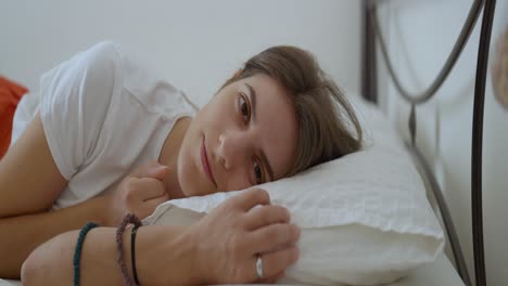Medium-close-up-shot-of-a-young-woman-waking-up-in-the-morning