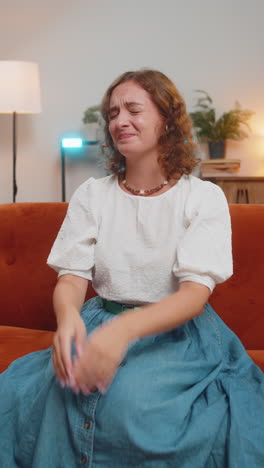 mujer joven triste sintiendo desesperanza soledad colapso nervioso llorando gritando sentada en el sofá
