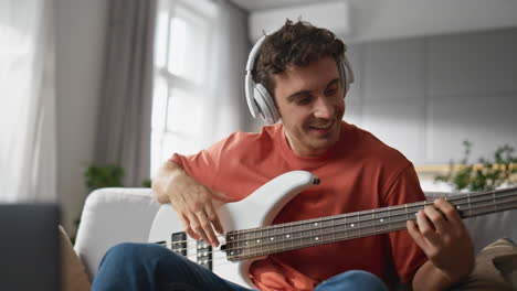 guitar teacher recording tutorial at cozy sofa closeup. happy guy looking laptop