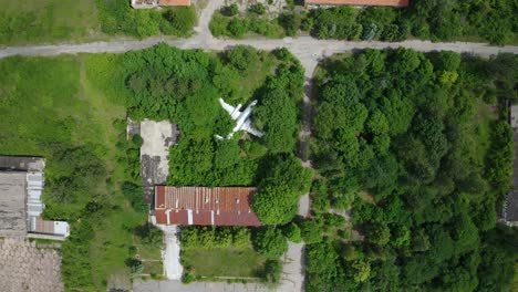 abandoned old airplane in the middle of green field, aerial top down