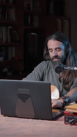 man playing acoustic guitar and recording with a laptop and microphone