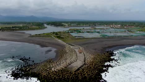 Powerful-ocean-and-industrial-salt-pans,-Glagah-Beach-Indonesia-shoreline-aerial