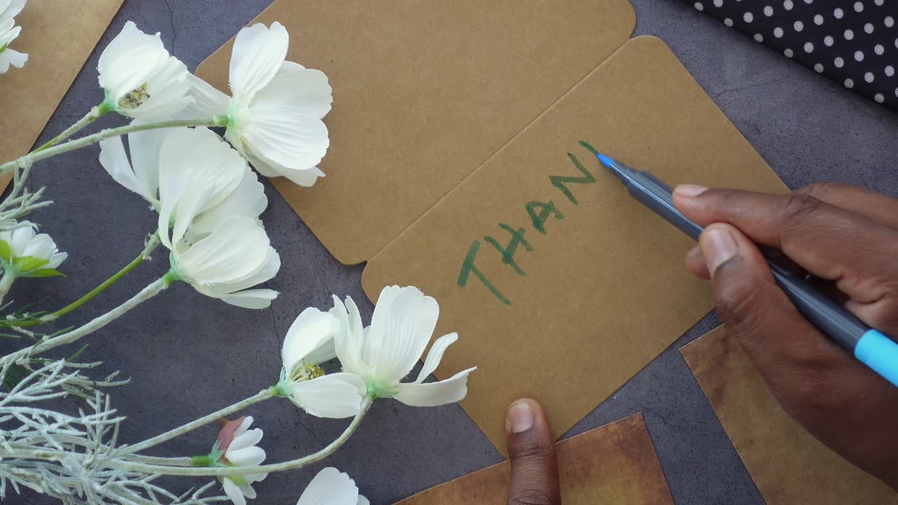 Skriver et takkekort med blomster