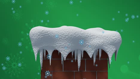 Snowflakes-falling-over-snow-covered-brick-wall-chimney-against-snowflakes-on-green-background