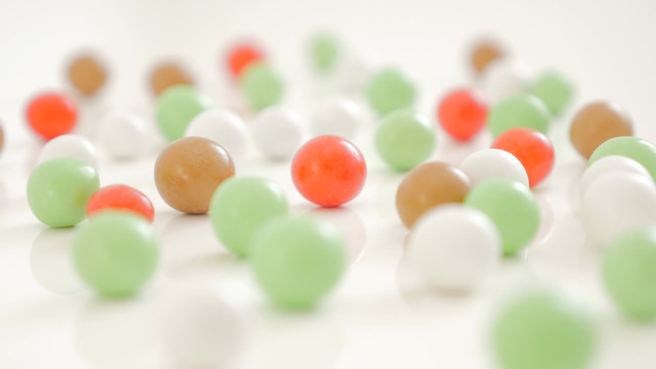 Bonbons arranged on white reflective background 4K
