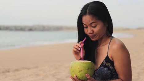 long hair thai girl is drinking fresh palm fruit juice by the shore