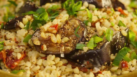 sprinkling greenery on bulgur with eggplant close-up rotation. traditional middle eastern culture. delicious rice with meat. arabian cuisine. homemade food concept