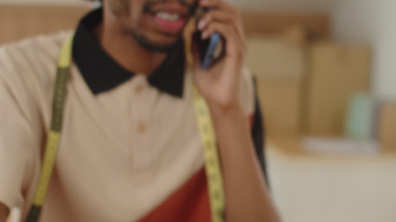 African American Seamster Having Phone Call about Dress Sketch