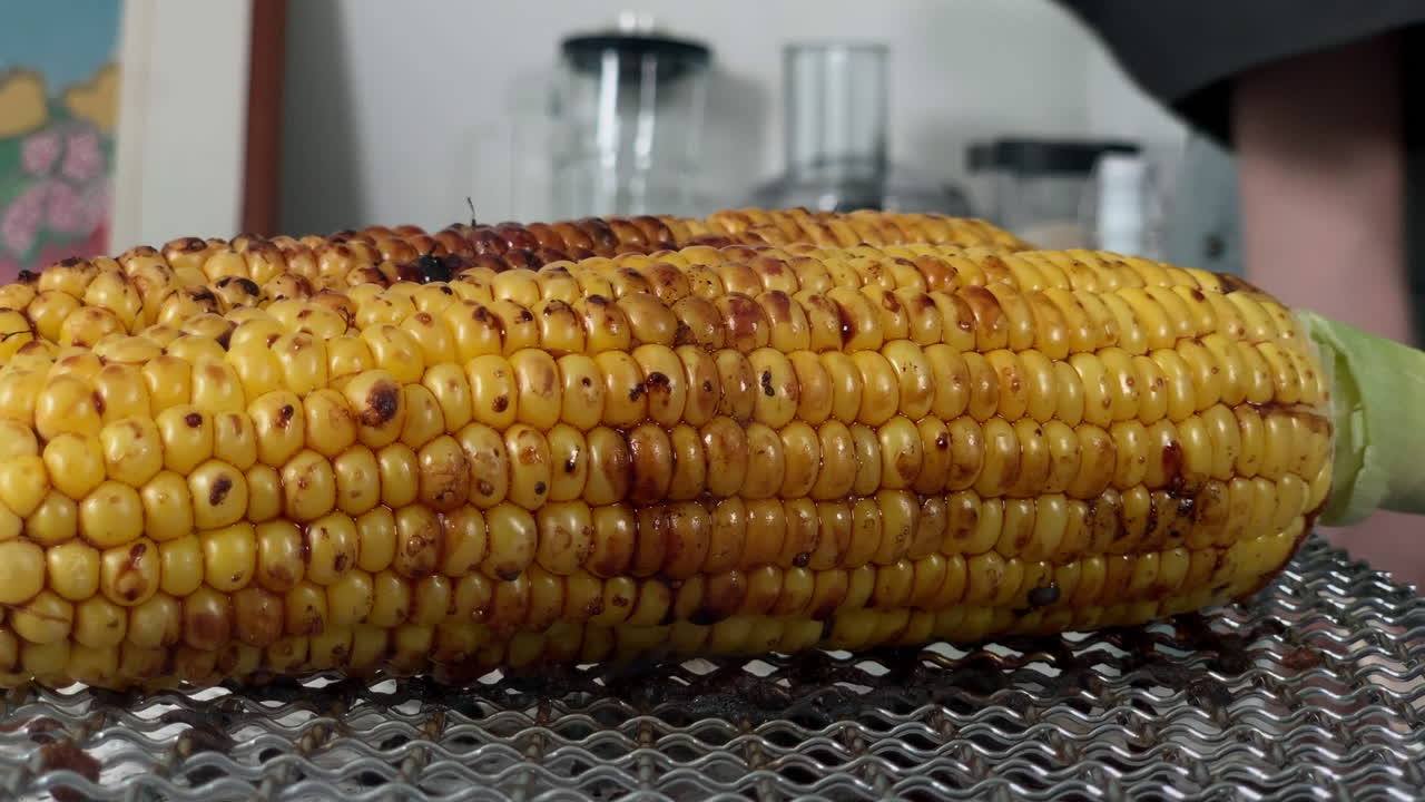 una chef japonesa pone shoyu en maíz a la parrilla en la cocina de su casa, tokio, japón