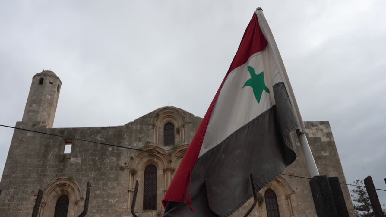 Syrian Flag in Front of Remains of Catholic Cathedral of Our Lady of Tortosa in Tortus