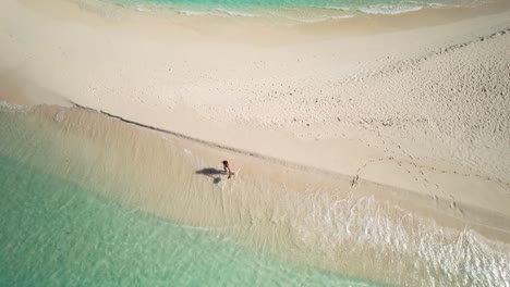 Toma-Aérea-Mujer-Latina-Caminando-En-La-Playa-De-Arena-Blanca-Solitaria-Isla-Caribeña-Exótica,-Los-Roques