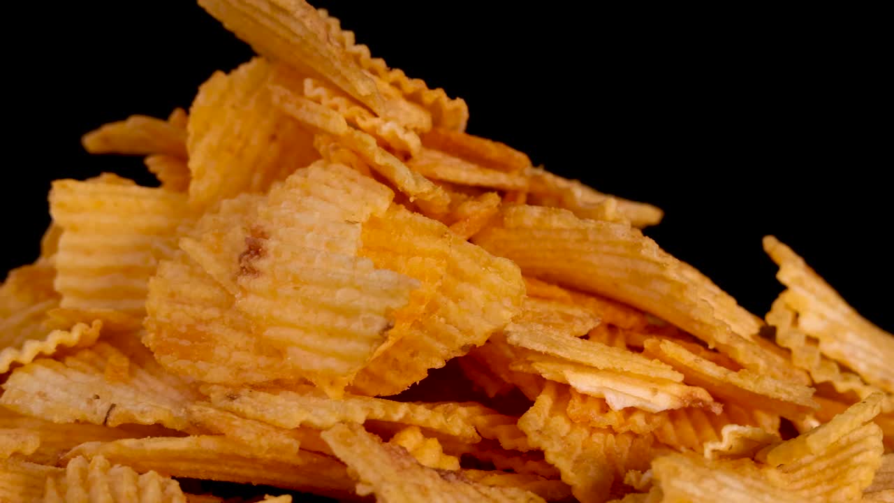 Patatine fritte dorate con creste ruotano delicatamente sotto luci da studio, rivelando la consistenza e la croccantezza