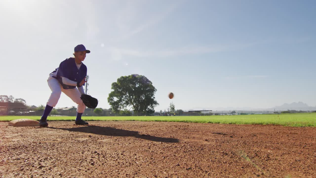 Giocatrice di campo di baseball di etnia mista che prende e lancia la palla su un campo da baseball soleggiato.