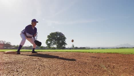 Mixed-race-female-baseball-fielder-catching-and-throwing-ball-on-sunny-baseball-field