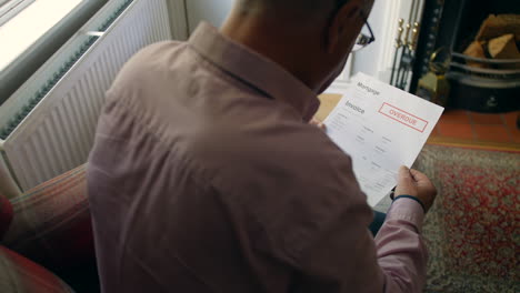 a lonely senior man opening a debt letter